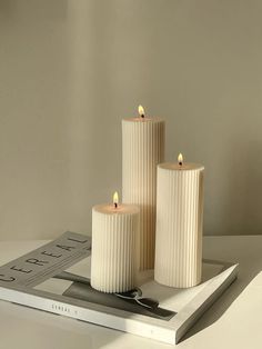 three white candles sitting on top of a table