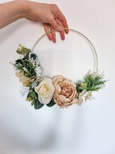 a hand holding a hoop with flowers and greenery