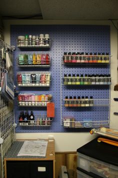 an organized craft room with pegboard and shelves filled with paint, supplies and tools