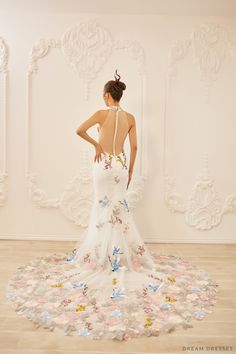 a woman in a white dress is standing on a floral rug with her back to the camera