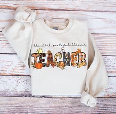 A cozy history teacher sweatshirt perfect for fall, Thanksgiving, and expressing gratitude. This unisex heavy blend crewneck sweatshirt is made with a medium-heavy fabric blend for those colder months, featuring a classic fit, crew neckline, and top-tier durability. Ideal for those who want to stay warm and show their thankfulness, this sweatshirt is a comfortable and stylish choice for anyone looking to stay cozy during the holiday season. Product features - Cozy unisex sweatshirt perfect for f White Sweatshirt For Teacher Appreciation In Fall, Fall Cotton Sweatshirt For Teacher Appreciation, Cotton Crew Neck T-shirt For Thanksgiving, Thankful Sweatshirt, Thankful And Blessed, History Teachers, Expressing Gratitude, Thanksgiving Gifts, Fall Thanksgiving