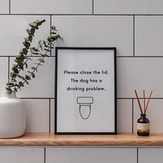 a white vase sitting on top of a wooden shelf next to a black and white poster