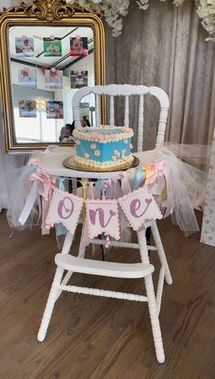 a blue and pink cake sitting on top of a white chair next to a mirror