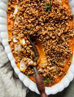 a white plate topped with meat covered in sauce and garnished with chopped herbs