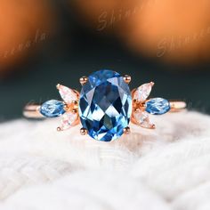 a blue ring sitting on top of a white furnishe covered surface with two pear shaped diamonds