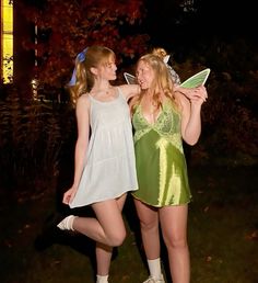 two young women dressed in green and white posing for the camera with one holding a butterfly