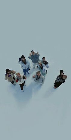 a group of people standing in the snow with their hands up and one person taking a selfie