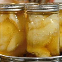 three jars filled with pickled bananas sitting on top of a metal tray next to another jar