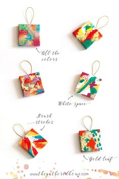 four square origami ornaments with different colors and designs on them, hanging from strings