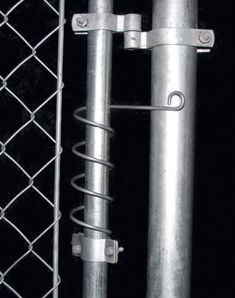 two metal poles are next to a chain - link fence and a wire mesh gate