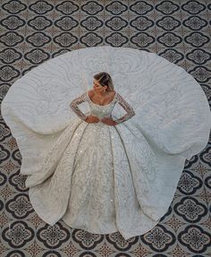 a woman in a white wedding dress laying on a patterned floor with her arms behind her back