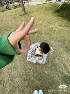 a person holding their hand out to another person's face in the middle of a grassy area