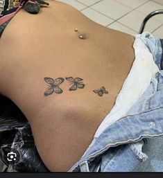 the back of a woman's stomach with three small butterflies on her left side