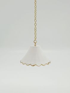 a white lamp hanging from a gold chain