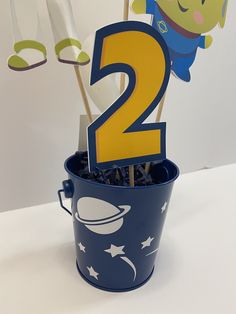 a blue bucket filled with cupcakes and two candles in the shape of numbers