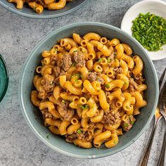 two bowls filled with macaroni and cheese on top of a marble countertop