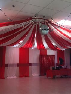 a red and white striped tent with disco ball hanging from it's centerpiece