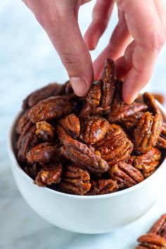 someone is picking up some pecans in a white bowl