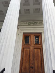 the front door to an old building with columns and doors on each side, which are decorated in white marble