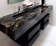 a large black marble counter top in a modern bathroom with white tile flooring and walls