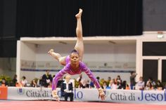 a woman is doing a handstand on a pink surface in front of an audience