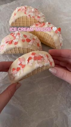 three ice cream tacos with hearts on them being held by someone's hand