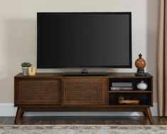 a flat screen tv sitting on top of a wooden entertainment center next to a window