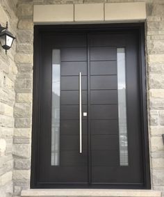 a black front door with two sidelights and a light on the wall next to it