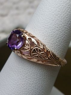 Natural Purple Amethyst Gold Ring Etched Wedding Design#160 Custom This stunning Victorian vintage reproduction ring in 10k rose gold has a brilliant natural purple amethyst gemstone. This full cut round cut genuine amethyst is 6mm in diameter. The inside of the band is marked 10k for gold. Notice the beautiful floral design of the gold filigree setting. This is a lovely rendition of an Antique filigree wedding ring. Make a spectacular statement about love and romance with this glorious solitair Gold Amethyst Ring For Wedding, Gold Amethyst Ring For Wedding, Round Cut, Heirloom Gold Amethyst Ring For Weddings, Amethyst Rings With Intricate Design For Wedding, Intricate Amethyst Wedding Ring, Heirloom Purple Amethyst Ring With Intricate Design, Heirloom Purple Ring For Wedding, Heirloom Purple Rings For Weddings, Vintage Lavender Jewelry For Wedding