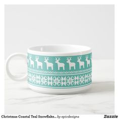 a cup with reindeers on it sitting on top of a marble counter next to a white wall