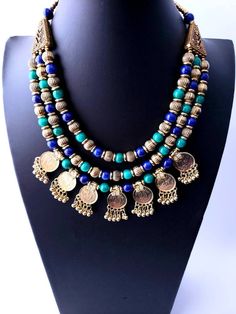 Vibrant blue green multi strand bib necklace with one row of stamped discs that resemble coins. This is an eye-catching fashion necklace due to the fresh color combination and the pleasing design. The discs are lightweight and quite shiny. Will dress up and freshen up any ensemble, Eastern or Western wear. Secure lobster clasp with an extension chain, ensures a perfect fit for you. View more unique necklaces: https://www.etsy.com/shop/BoutiqueByMaryam?section_id=21694658 Shop BoutiqueByMaryam: h Blue Bohemian Beads For Festive Occasion, Bohemian Blue Beads For Festive Occasions, Handmade Bohemian Coin Necklace, Bohemian Blue Round Beads, Bohemian Beaded Coin Necklace For Gift, Bohemian Round Medallion Necklace For Festival, Blue Bohemian Necklaces For Festive Occasions, Blue Bohemian Necklace For Festive Occasions, Bohemian Blue Beaded Necklace For Festivals