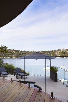 a deck with chairs and an umbrella overlooking the water