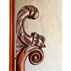 an ornate wooden carving on the side of a door with a mirror in the background