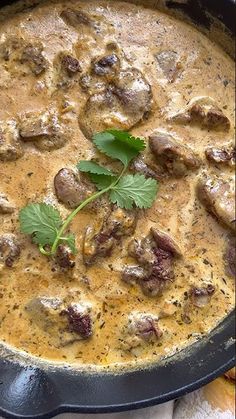 a pan filled with meat and vegetables covered in gravy, garnished with cilantro