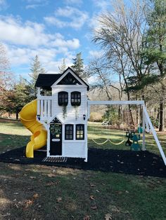 a white house with a yellow slide in the yard