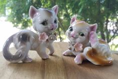 two ceramic cats sitting on top of a wooden table