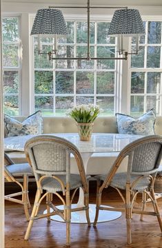 a dining room table with four chairs and a bench in front of the large window