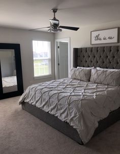 a bedroom with a large bed, mirror and ceiling fan in it's corner