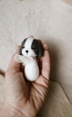 a hand holding a small stuffed animal in it's left hand on top of a piece of paper