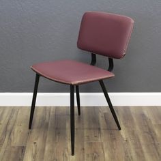 a purple chair sitting on top of a hard wood floor next to a gray wall