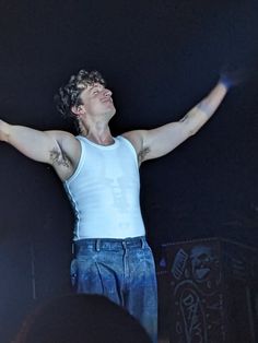 a man with his arms up in the air while standing on stage at a concert