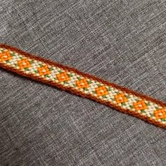 an orange and white beaded bracelet sitting on top of a gray cloth