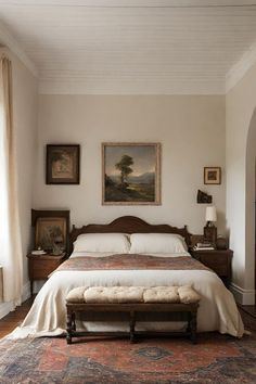 a bedroom with a large bed and paintings on the wall