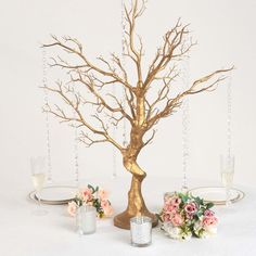 there is a gold tree on the table with flowers and candles around it, along with other decorations