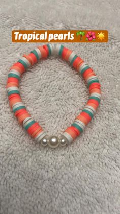 an orange, green and white beaded bracelet with a silver ball on the end