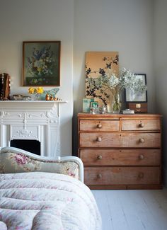 a bedroom with a bed, dresser and painting on the wall