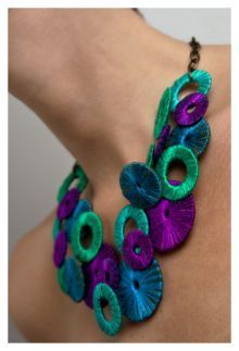 a close up of a woman's neck wearing a purple and green necklace with flowers on it