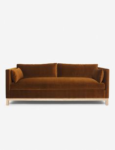 a brown velvet couch with two pillows on it's arms and back, against a white background