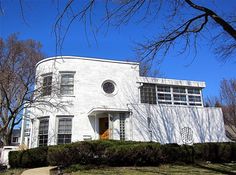 a large white house sitting on top of a lush green field next to trees and bushes