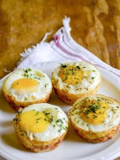 three eggs are sitting on top of small muffins with chives and parsley